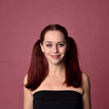 Pembe stüdyo arka planında anlamlı yüz hatları olan kızıl saçlı bir kadının portresi..