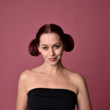 Pembe stüdyo arka planında anlamlı yüz hatları olan kızıl saçlı bir kadının portresi..