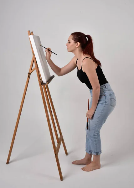Pełnowymiarowy Portret Rudej Artystki Dżinsach Koszulce Stojąca Pozycja Malująca Płótno — Zdjęcie stockowe