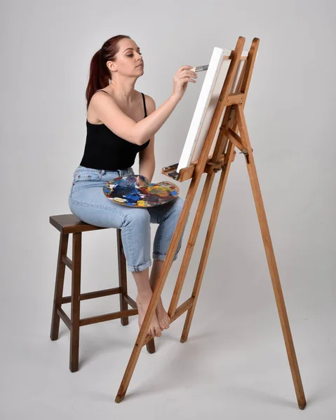 Pełny Portret Rudej Artystki Dżinsach Białej Koszuli Siedząc Krześle Malując — Zdjęcie stockowe