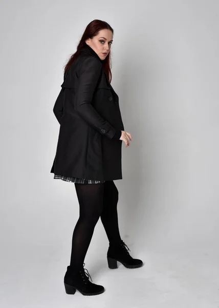 터틀넥 스웨터에 격자무늬 치마와 부츠를 소녀의 스튜디오 배경에 카메라 포즈를 — 스톡 사진