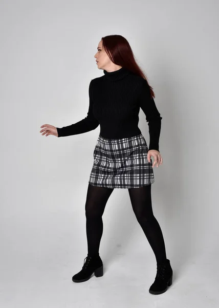 터틀넥 스웨터에 격자무늬 치마와 부츠를 소녀의 스튜디오 배경에 나란히 — 스톡 사진