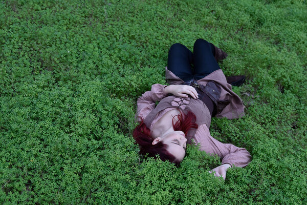  portrait of red haired girl wearing fantasy medieval clothes of a wandering adventurer.  natural light in a woodland forest setting.