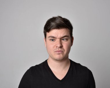 Bir esmerin kafa ve omuz portresini kapat. Çeşitli yüz ifadeleri olan genç bir adam. Açık gri stüdyo arka planında izole edilmiş..