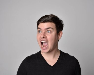 Bir esmerin kafa ve omuz portresini kapat. Çeşitli yüz ifadeleri olan genç bir adam. Açık gri stüdyo arka planında izole edilmiş..