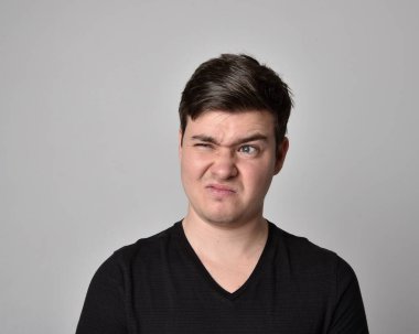 Bir esmerin kafa ve omuz portresini kapat. Çeşitli yüz ifadeleri olan genç bir adam. Açık gri stüdyo arka planında izole edilmiş..