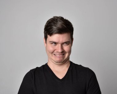 Bir esmerin kafa ve omuz portresini kapat. Çeşitli yüz ifadeleri olan genç bir adam. Açık gri stüdyo arka planında izole edilmiş..