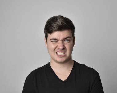 Bir esmerin kafa ve omuz portresini kapat. Çeşitli yüz ifadeleri olan genç bir adam. Açık gri stüdyo arka planında izole edilmiş..