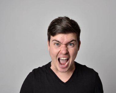 Bir esmerin kafa ve omuz portresini kapat. Çeşitli yüz ifadeleri olan genç bir adam. Açık gri stüdyo arka planında izole edilmiş..