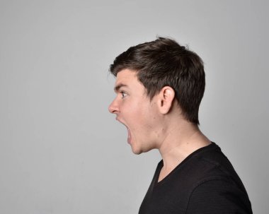 Bir esmerin kafa ve omuz portresini kapat. Çeşitli yüz ifadeleri olan genç bir adam. Açık gri stüdyo arka planında izole edilmiş..