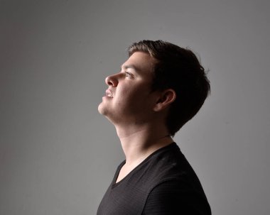 Bir esmerin kafa ve omuz portresini kapat. Çeşitli yüz ifadeleri olan genç bir adam. Açık gri stüdyo arka planında izole edilmiş..