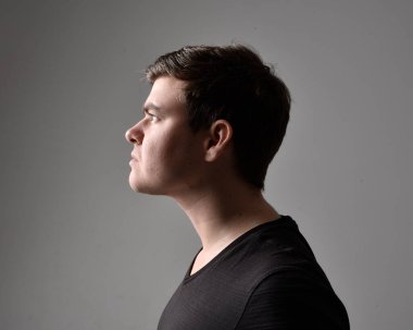 Bir esmerin kafa ve omuz portresini kapat. Çeşitli yüz ifadeleri olan genç bir adam. Açık gri stüdyo arka planında izole edilmiş..