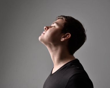 Bir esmerin kafa ve omuz portresini kapat. Çeşitli yüz ifadeleri olan genç bir adam. Açık gri stüdyo arka planında izole edilmiş..