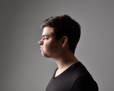 Bir esmerin kafa ve omuz portresini kapat. Çeşitli yüz ifadeleri olan genç bir adam. Açık gri stüdyo arka planında izole edilmiş..