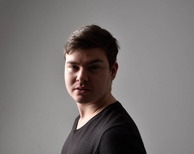 Bir esmerin kafa ve omuz portresini kapat. Çeşitli yüz ifadeleri olan genç bir adam. Açık gri stüdyo arka planında izole edilmiş..