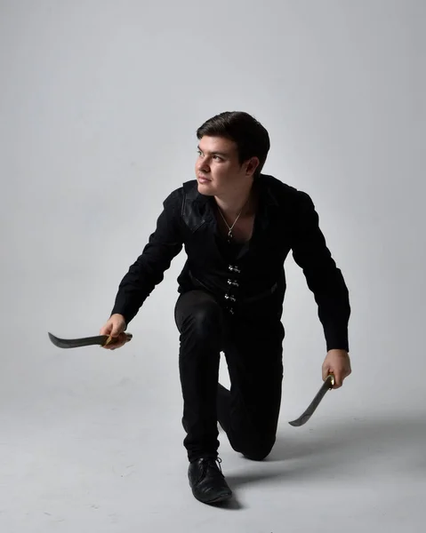 黒いシャツを着たブルネットの男と剣を持つゴシックのウエストコートの完全な長さの肖像画 灰色のスタジオの背景に隔離された立ち動作ポーズ — ストック写真