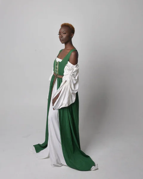 長い緑の中世のファンタジーガウンを身に着けているかなりアフリカの女性の完全な長さの肖像画 立って踊るポーズ上のライトグレーのスタジオの背景 — ストック写真