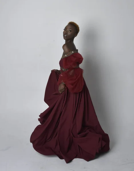 美しいですアフリカの女性の完全な長さの肖像画身に着けています長い赤ルネッサンス中世のファンタジーガウン 立ちポーズ上のライトグレーのスタジオの背景 — ストック写真