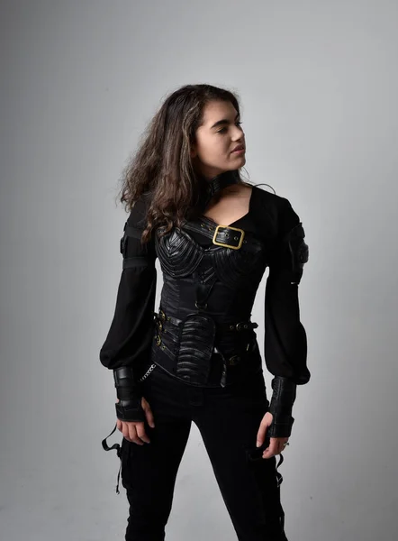 穿着紧身衣的黑色皮革科幻套装 站在浅灰工作室背景上的年轻女性近照 — 图库照片