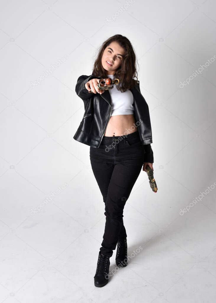 Full length portrait of young woman with natural brown hair,  wearing black leather scifi outfit with jacket, standing pose on light studio background.