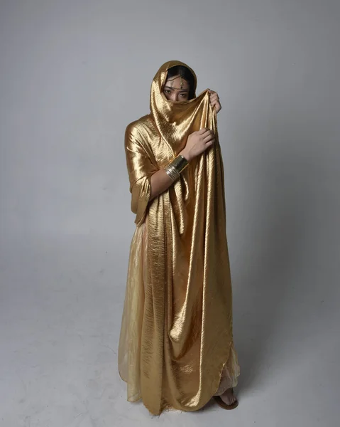 황금색 아라비아 예복을 스튜디오 배경에 고립된 채흐르는 아시아인 여성의 — 스톡 사진