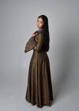 Orta çağ fantezi elbisesi giymiş uzun saçlı güzel Asyalı bir kadının tam boy portresi. Stüdyonun arka planında soyutlanmış, zarif bir duruş sergiledi..