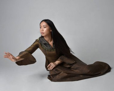 Orta çağ fantezi elbisesi giymiş uzun saçlı güzel Asyalı bir kadının tam boy portresi. Zarif bir poz, stüdyo arka planında izole..