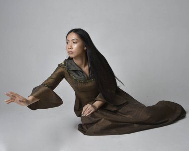 Orta çağ fantezi elbisesi giymiş uzun saçlı güzel Asyalı bir kadının tam boy portresi. Zarif bir poz, stüdyo arka planında izole..