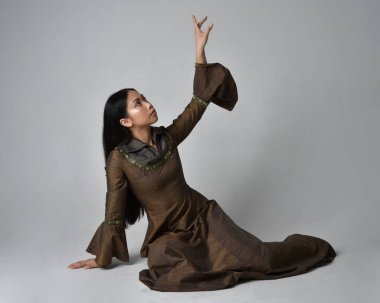 Orta çağ fantezi elbisesi giymiş uzun saçlı güzel Asyalı bir kadının tam boy portresi. Zarif bir poz, stüdyo arka planında izole..