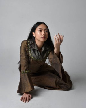 Orta çağ fantezi elbisesi giymiş uzun saçlı güzel Asyalı bir kadının tam boy portresi. Zarif bir poz, stüdyo arka planında izole..