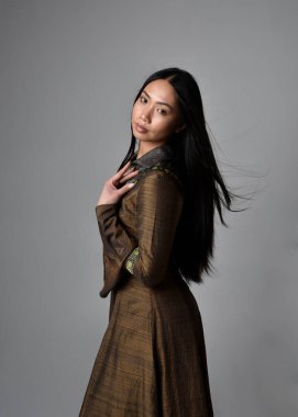 Orta çağ fantezi elbisesi giymiş, uzun saçlı güzel Asyalı bir kadının portresi. Hareketli elleri olan zarif bir poz, stüdyo arka planında izole edilmiş..