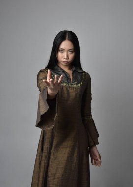 Orta çağ fantezi elbisesi giymiş, uzun saçlı güzel Asyalı bir kadının portresi. Hareketli elleri olan zarif bir poz, stüdyo arka planında izole edilmiş..