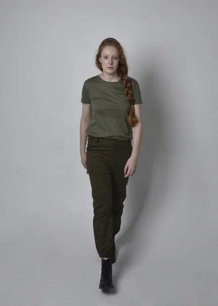 全长肖像漂亮的红头发女人穿着陆军绿色卡其布衬衫 实用的裤子和靴子 独立于工作室背景的站立姿势 — 图库照片