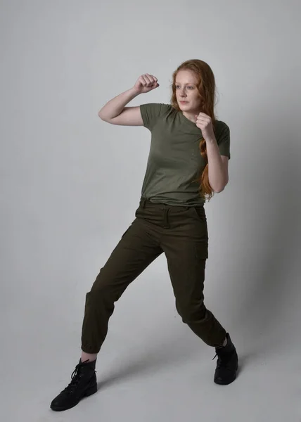全长肖像漂亮的红头发女人穿着陆军绿色卡其布衬衫 实用的裤子和靴子 独立于工作室背景的站立姿势 — 图库照片
