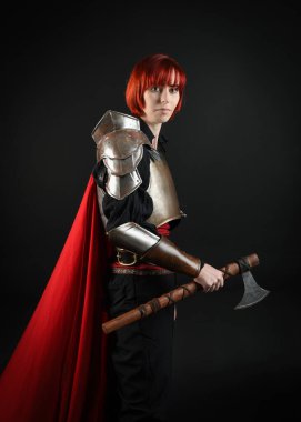 Savaşçı kadın şövalyenin fantezi portresi, tarihi ortaçağ zırhı giymiş bir model, kırmızı peri masalı pelerini. Savaş baltası, izole stüdyo geçmişi..