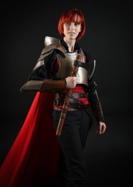 Savaşçı kadın şövalyenin fantezi portresi, tarihi ortaçağ zırhı giymiş bir model, kırmızı peri masalı pelerini. Savaş baltası, izole stüdyo geçmişi..