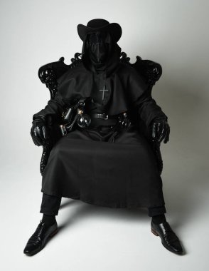 Fenerli Gotik Veba Doktoru, Kara Pelerinli Cadılar Bayramı Karakteri, Kuş Maskeli, kadife taht koltuğunda oturan. Gizemli Fantezi Korku figürünün Stüdyo Portresi