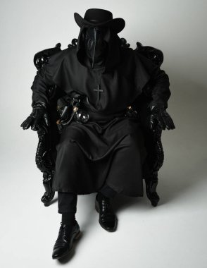 Fenerli Gotik Veba Doktoru, Kara Pelerinli Cadılar Bayramı Karakteri, Kuş Maskeli, kadife taht koltuğunda oturan. Gizemli Fantezi Korku figürünün Stüdyo Portresi