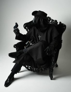 Fenerli Gotik Veba Doktoru, Kara Pelerinli Cadılar Bayramı Karakteri, Kuş Maskeli, kadife taht koltuğunda oturan. Gizemli Fantezi Korku figürünün Stüdyo Portresi