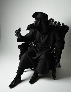 Fenerli Gotik Veba Doktoru, Kara Pelerinli Cadılar Bayramı Karakteri, Kuş Maskeli, kadife taht koltuğunda oturan. Gizemli Fantezi Korku figürünün Stüdyo Portresi