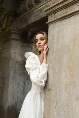Beyaz fantezi gelinlik giyen güzel sarışın manken figürü. Tarihi masal şatosunun kapısında yürüyorum. 