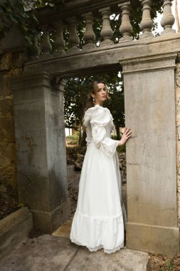 Beyaz fantezi gelinlik giyen güzel sarışın mankenin uzun boylu kadın figürü. Tarihi masal şatosunun kapısında yürüyorum. 