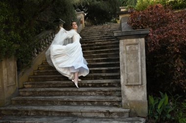 Tarihi beyaz gelinlik ve fantezi pelerin giyen güzel sarışın mankenin portresi. Peri masalı şatosunun tarihi merdivenlerinde yürüyen ruhani bir figür..