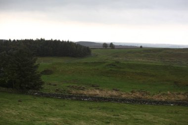 Antik Roma İmparatorluğu anıtı Hadrians Duvarı 'nın engebeli İskoç dağlık kırsalındaki sinematik manzarası rüzgarlı bir bozkıra çarpan tarihi bir dönüm noktası.