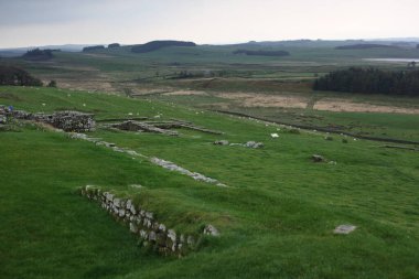 Antik Roma İmparatorluğu anıtı Hadrians Duvarı 'nın engebeli İskoç dağlık kırsalındaki sinematik manzarası rüzgarlı bir bozkıra çarpan tarihi bir dönüm noktası.