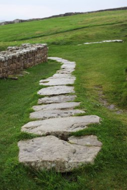 Antik Roma İmparatorluğu anıtı Hadrians Duvarı 'nın engebeli İskoç dağlık kırsalındaki sinematik manzarası rüzgarlı bir bozkıra çarpan tarihi bir dönüm noktası.