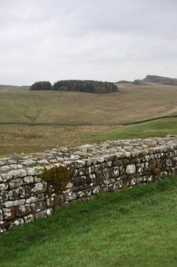 Antik Roma İmparatorluğu anıtı Hadrians Duvarı 'nın engebeli İskoç dağlık kırsalındaki sinematik manzarası rüzgarlı bir bozkıra çarpan tarihi bir dönüm noktası.