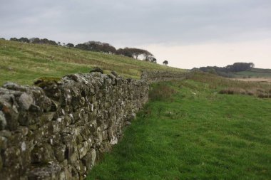 Antik Roma İmparatorluğu anıtı Hadrians Duvarı 'nın engebeli İskoç dağlık kırsalındaki sinematik manzarası rüzgarlı bir bozkıra çarpan tarihi bir dönüm noktası.