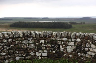 Antik Roma İmparatorluğu anıtı Hadrians Duvarı 'nın engebeli İskoç dağlık kırsalındaki sinematik manzarası rüzgarlı bir bozkıra çarpan tarihi bir dönüm noktası.