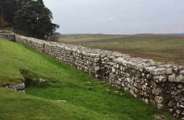 Antik Roma İmparatorluğu anıtı Hadrians Duvarı 'nın engebeli İskoç dağlık kırsalındaki sinematik manzarası rüzgarlı bir bozkıra çarpan tarihi bir dönüm noktası.